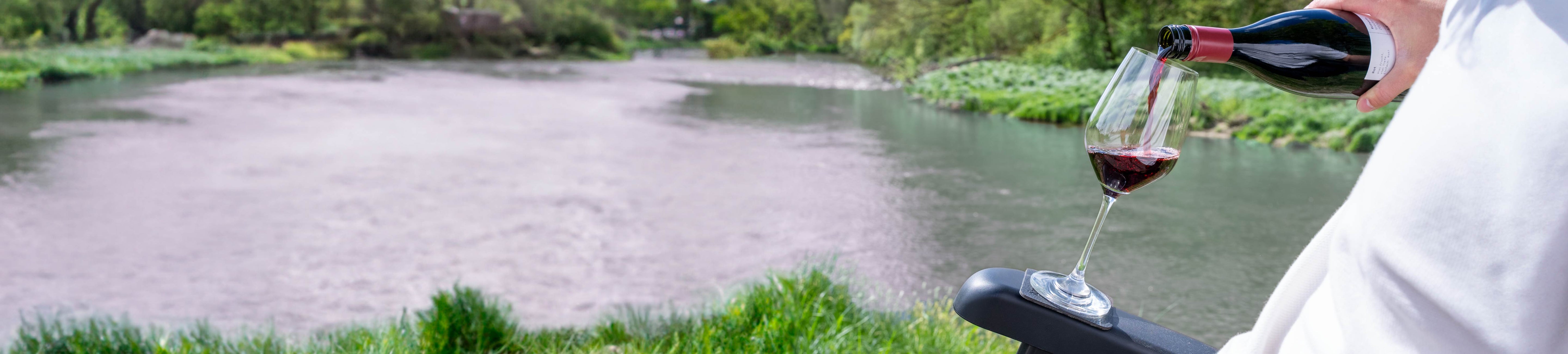 Magnet-Kristallglas Wein wird mit Wein befüllt, während es auf einem Pad auf einer Armlehne eines Campingstuhls steht