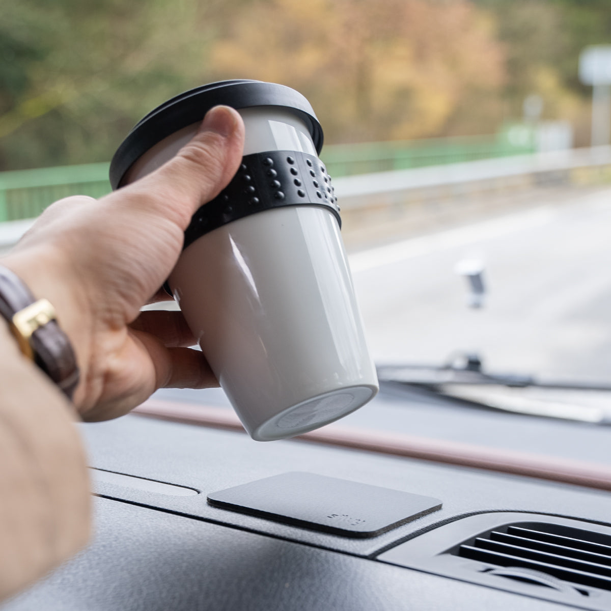 Porcelain cup with magnet is placed on pad on dashboard