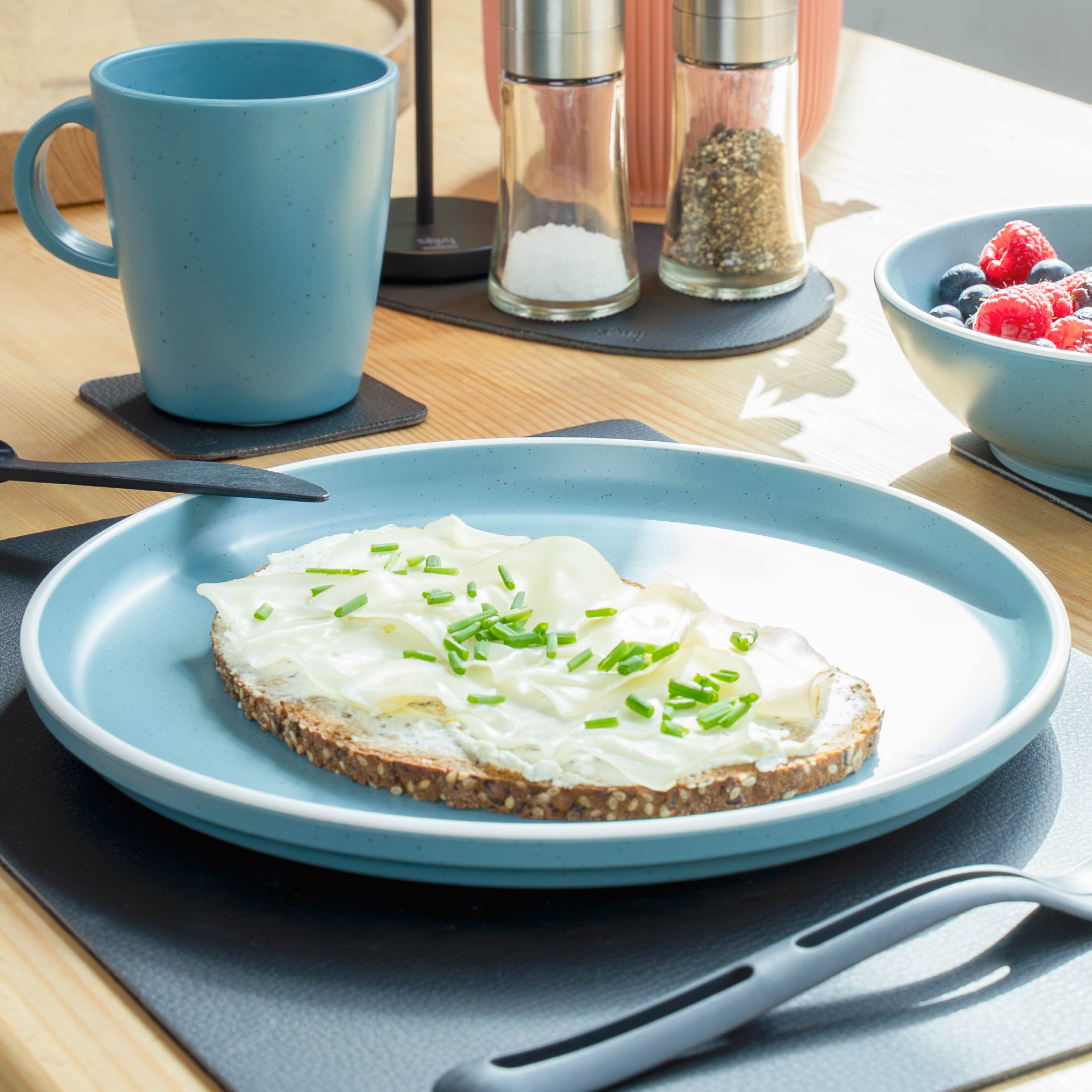 Blue plastic crockery set on mat in kitchen environment