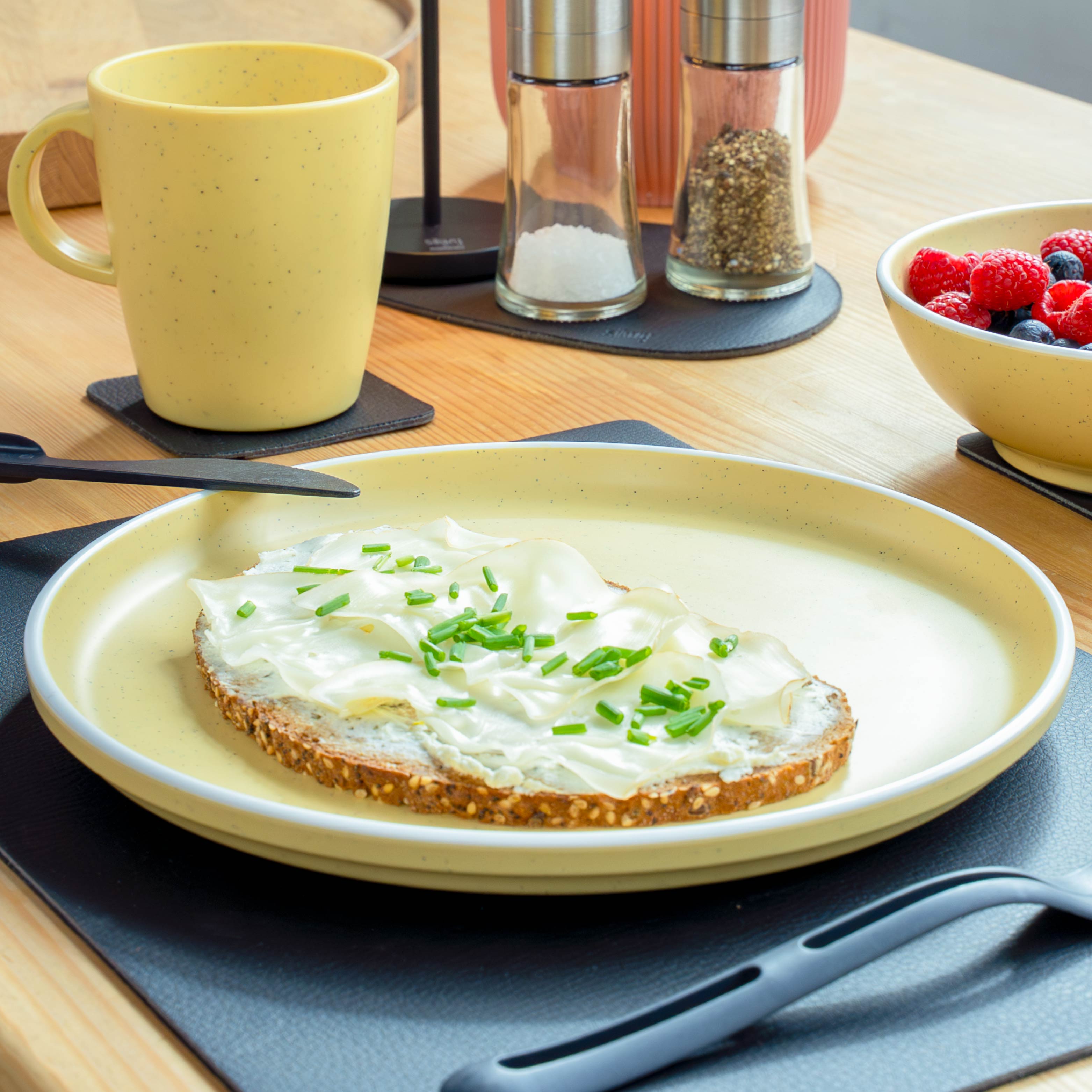 Yellow plastic crockery set on mat in kitchen environment