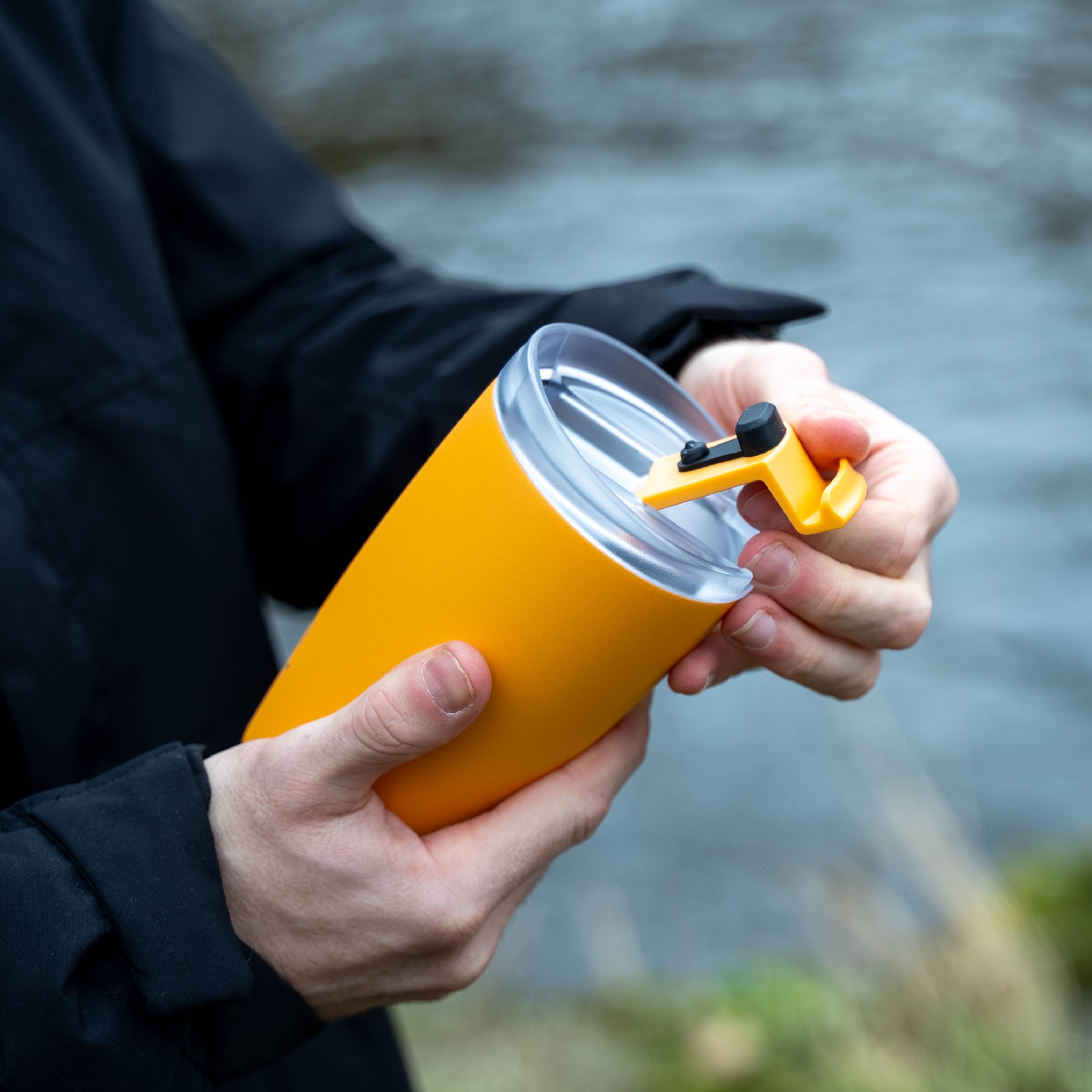 The silwy x FLSK Thermocup in the color sunrise is opened and held in the hand