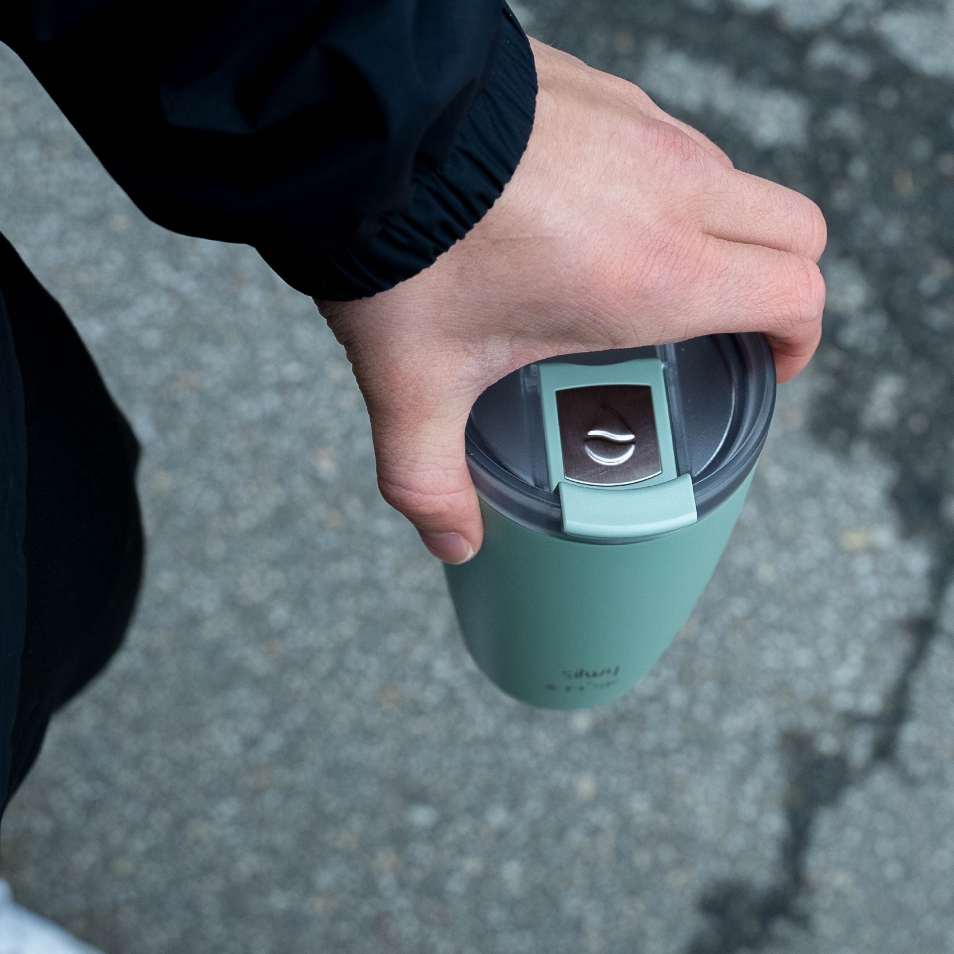 The silwy x FLSK Thermocup in the color sage, with closed lid is held from above