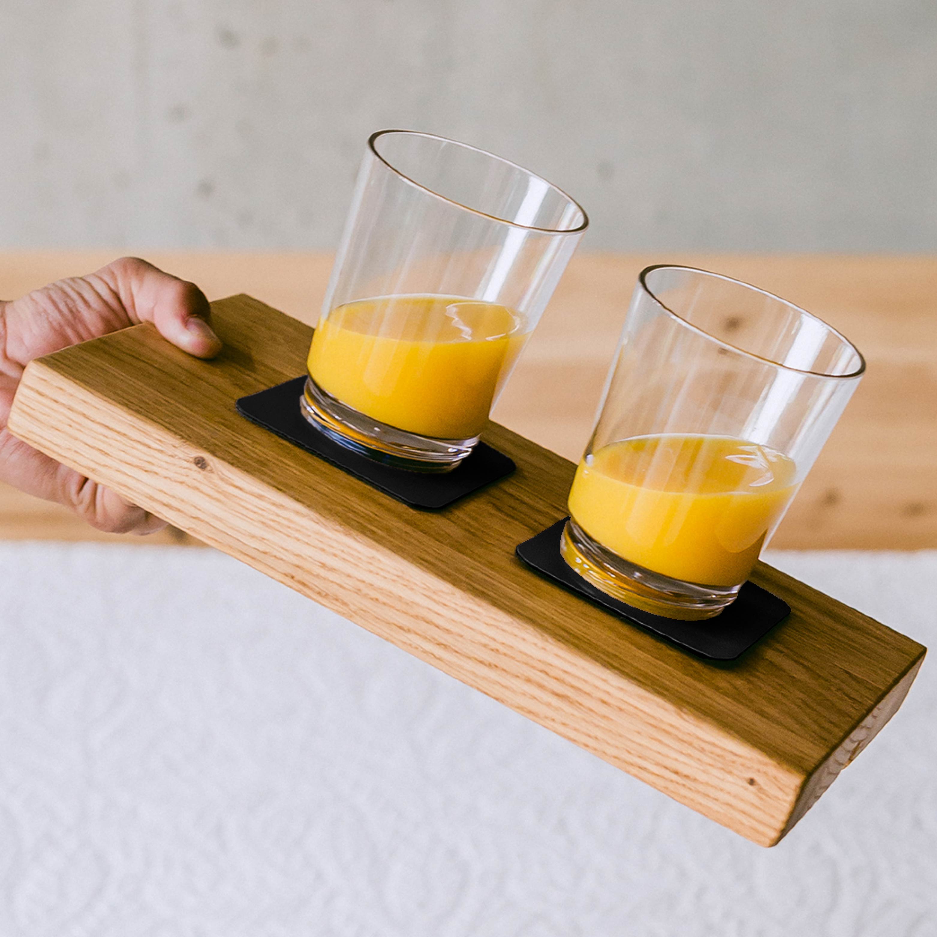 Magnetic glasses filled with orange juice on the corresponding Metal-Nano-Gel-Pads attached to the wooden surface