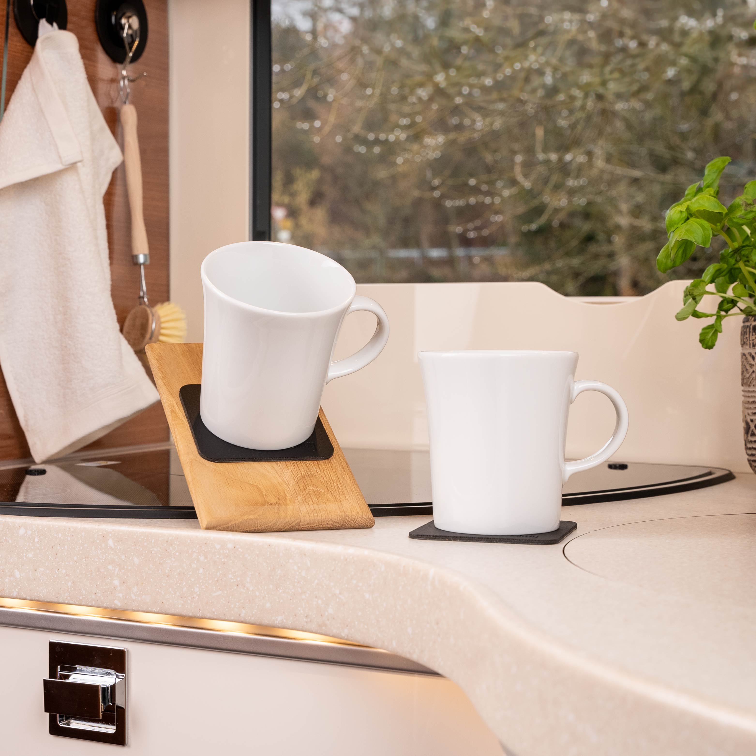 Tazas con asas magnéticas colocadas sobre almohadillas, en una superficie inclinada en una autocaravana