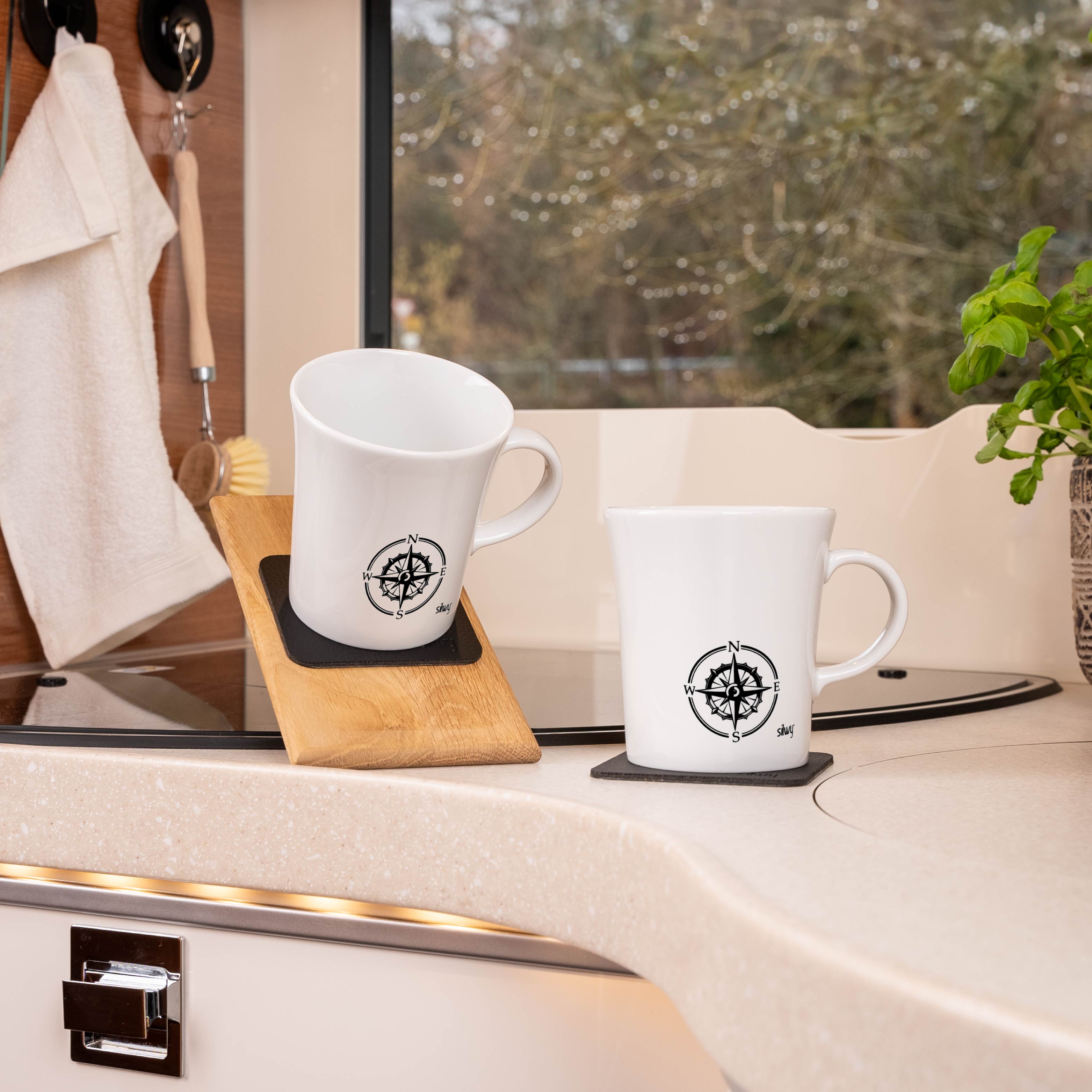 Tazas con asas magnéticas colocadas sobre almohadillas, en una superficie inclinada en una autocaravana
