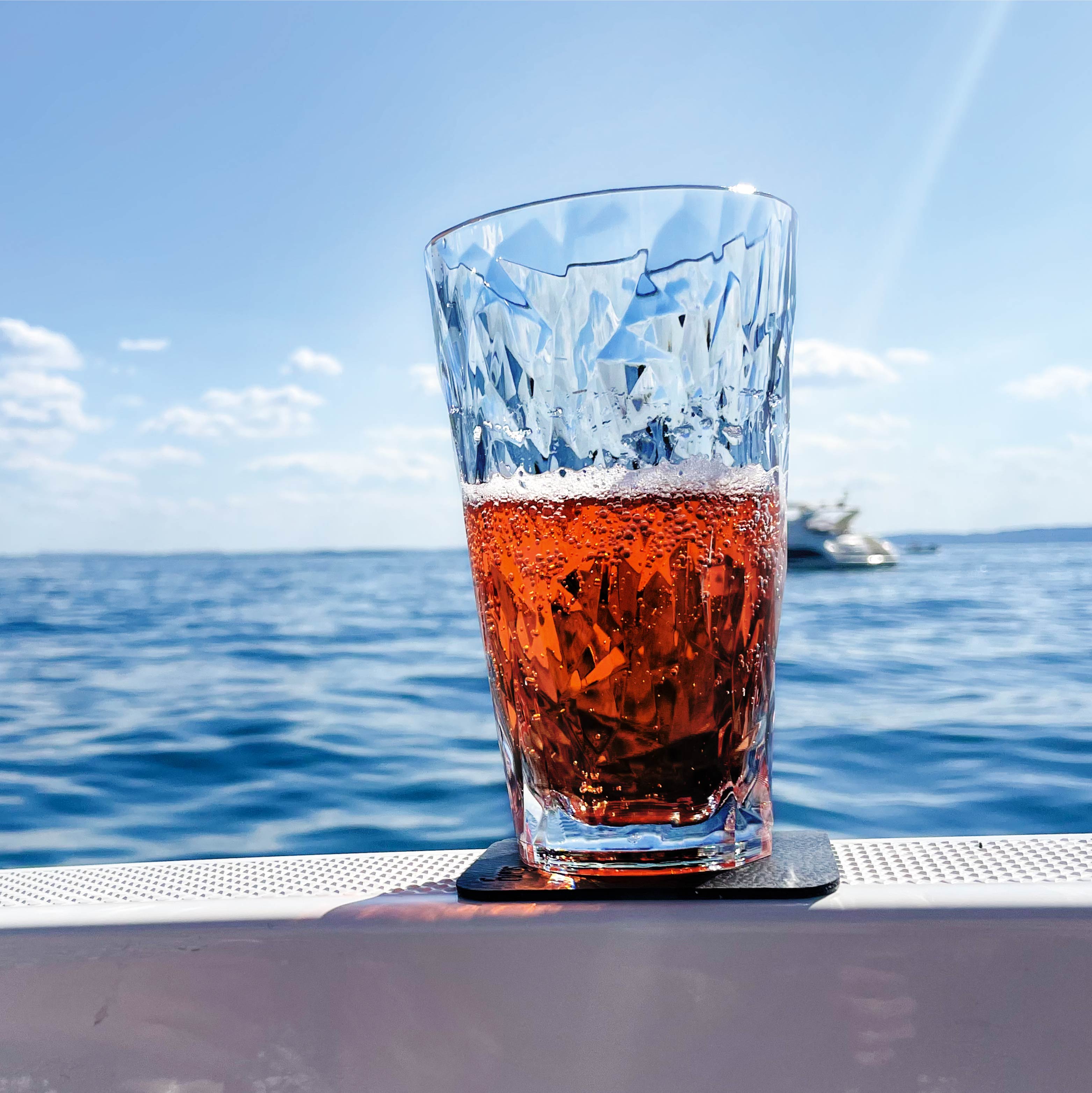 Vaso magnético de plástico Longdrink colocado en una almohadilla en un barco durante el viaje