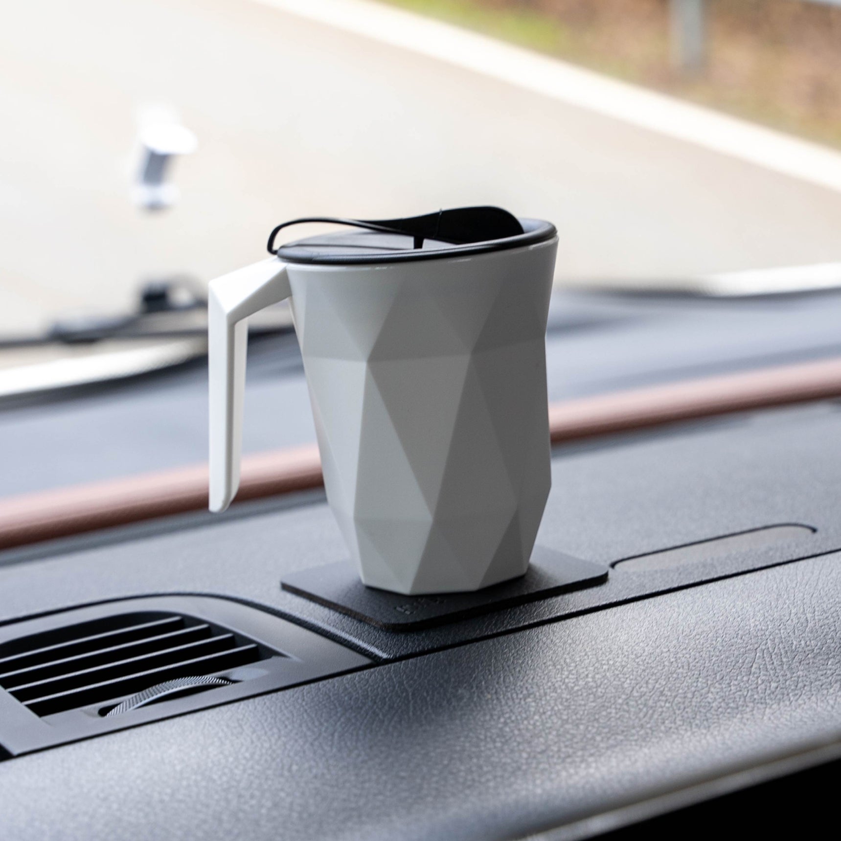 Taza TO-GO de plástico magnética sobre almohadilla cuadrada negra en coche