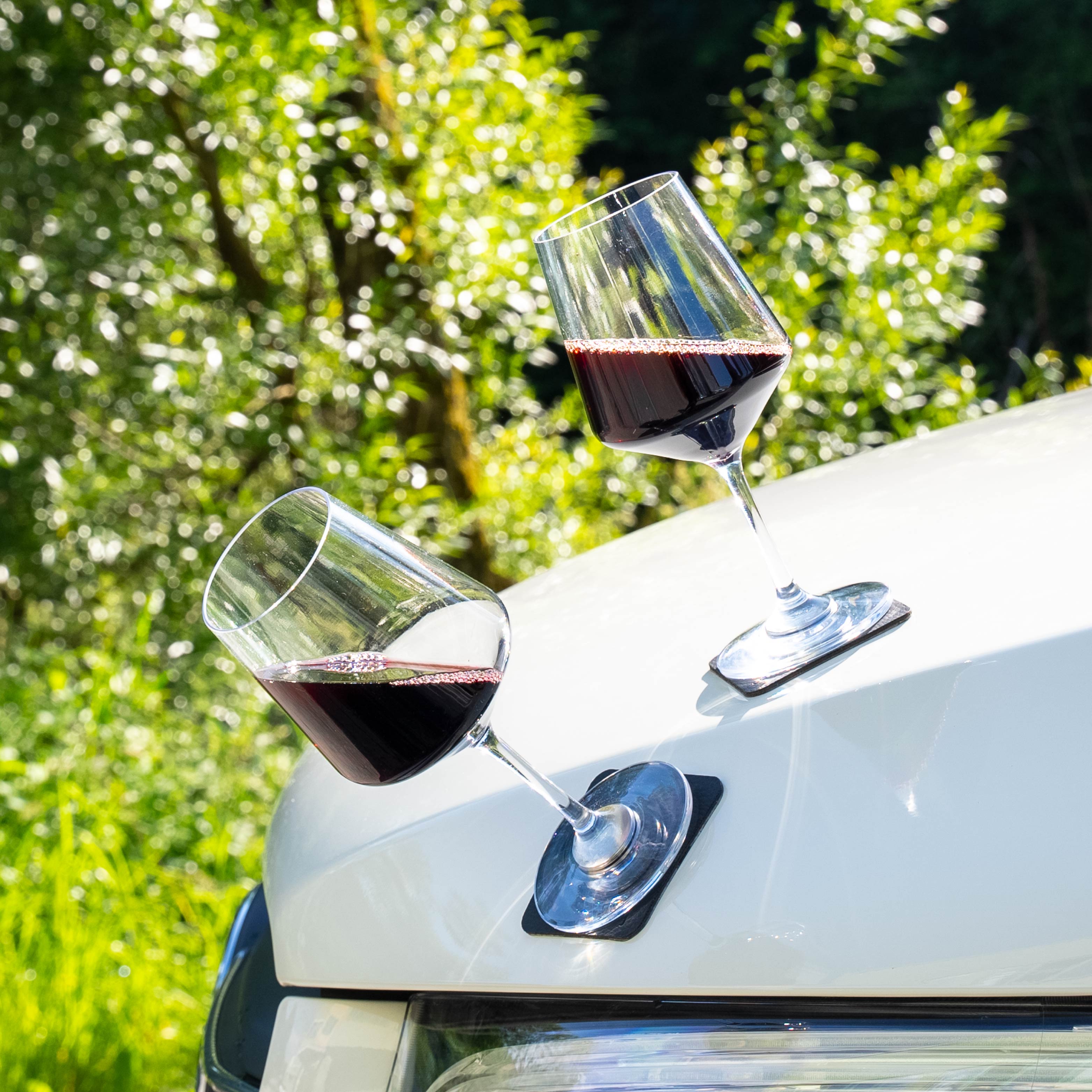 Bicchieri di vino magnetici in plastica posti su un cofano di metallo
