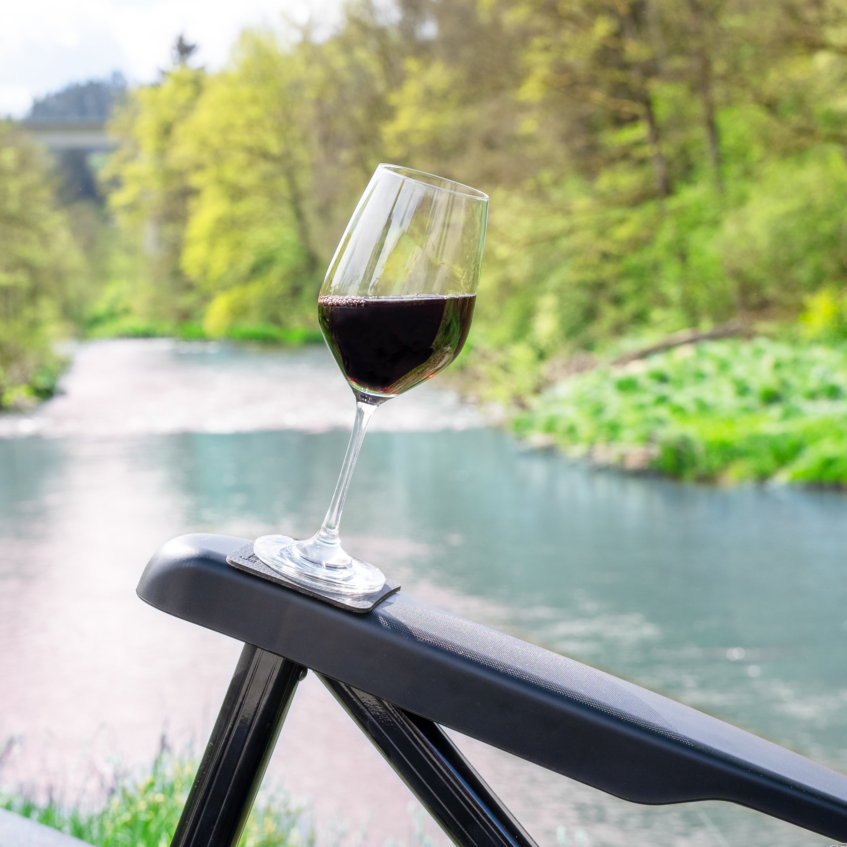 Magnet-Kristallglas Wein gefüllt mit Rotwein auf der Armlehne eines Stuhls auf einem quadratischen Metall-Nano-Gel-Pad 