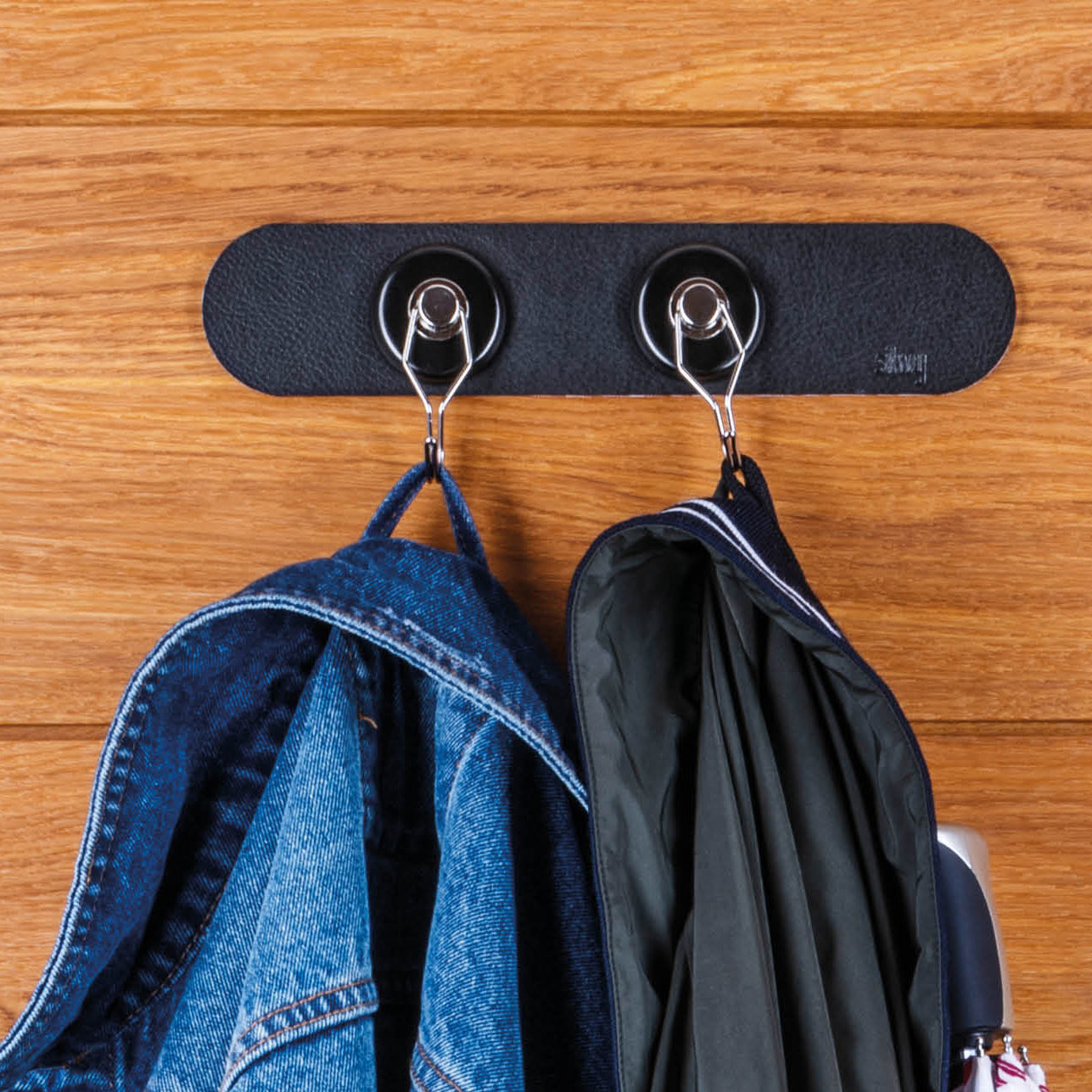 Magnetic hook with black Metal Strip and jackets hanging from it 