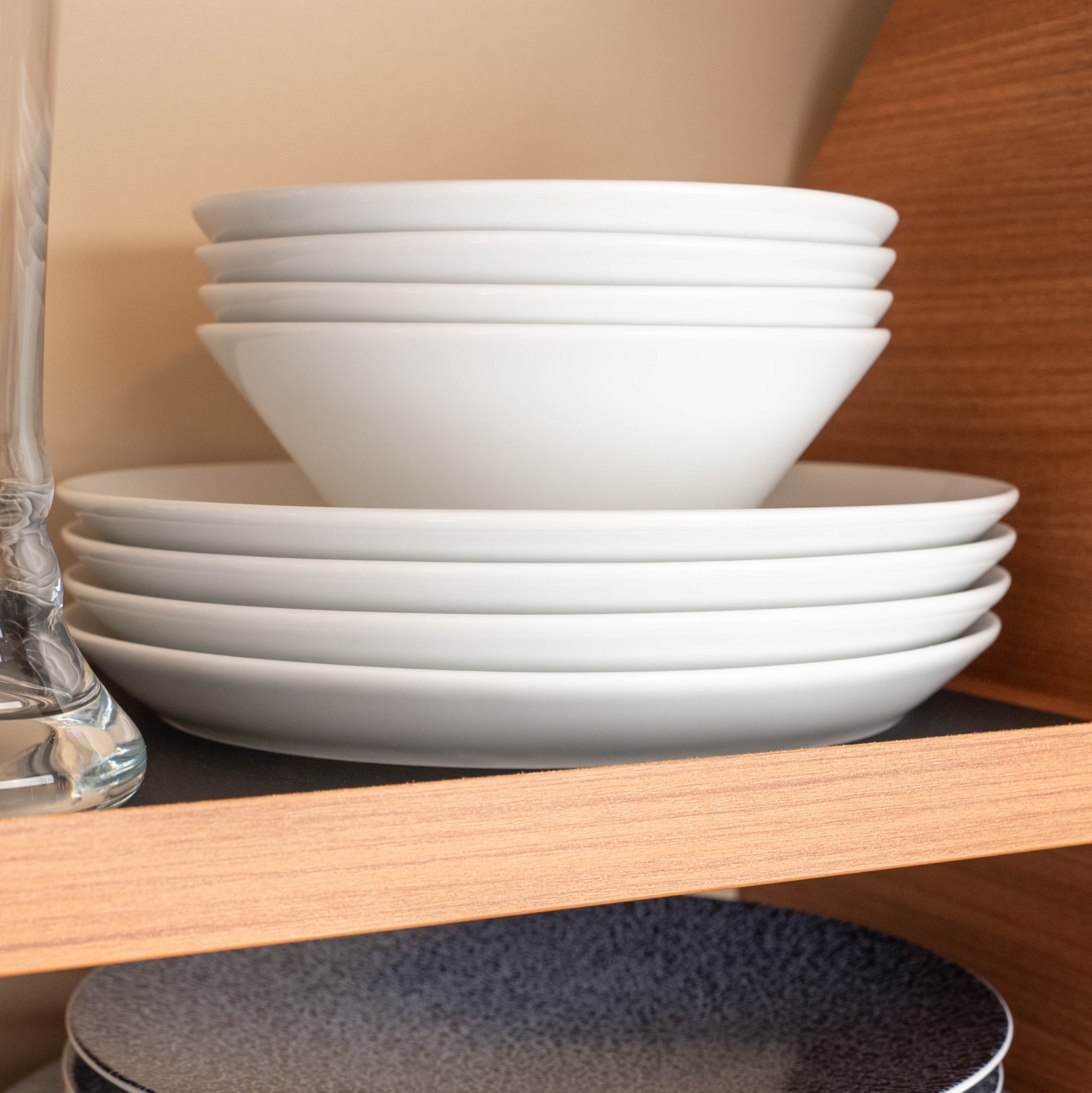 Magnetic porcelain Bowls and magnetic porcelain plates stacked on top of each other on a shelf 
