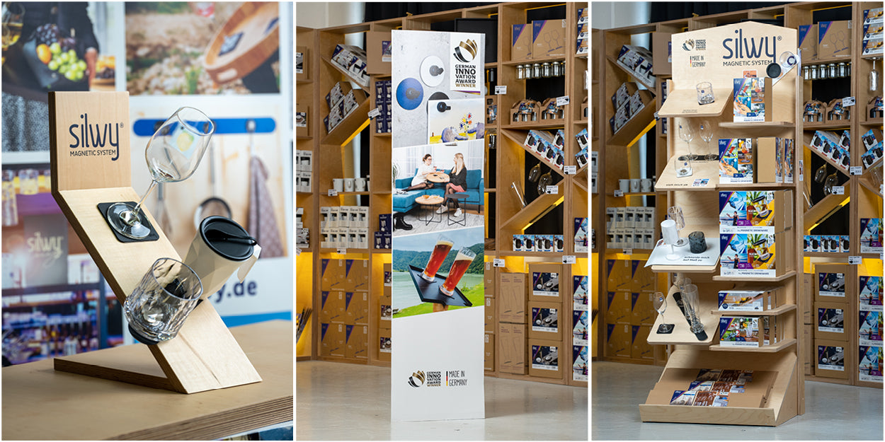 Photo 1: wooden, slate silwy display with a Magnetic crystal glass wine, a Magnetic plastic glass tumbler and the white Magnetic plastic cup TO-GO; Photo 2: cardboard display with photos in front of shelves filled with silwy products; Photo 3: wooden silwy display in front of shelves filled with silwy products 