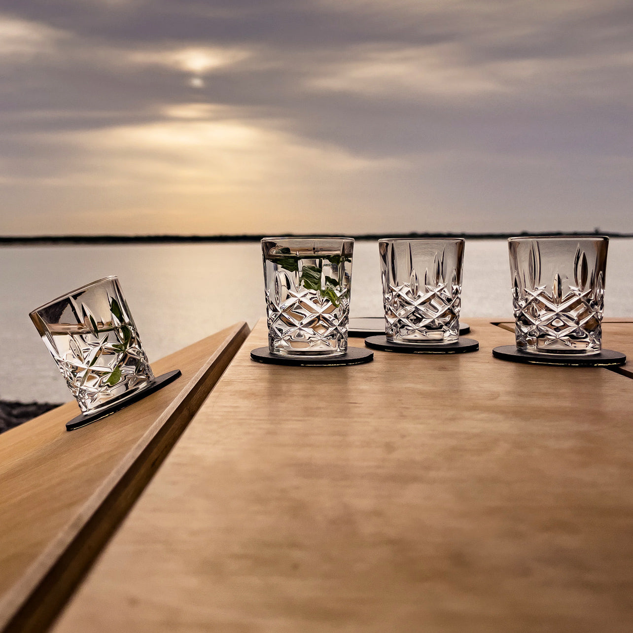 Four crystal glasses of whisky on table with Metal nano gel pads 