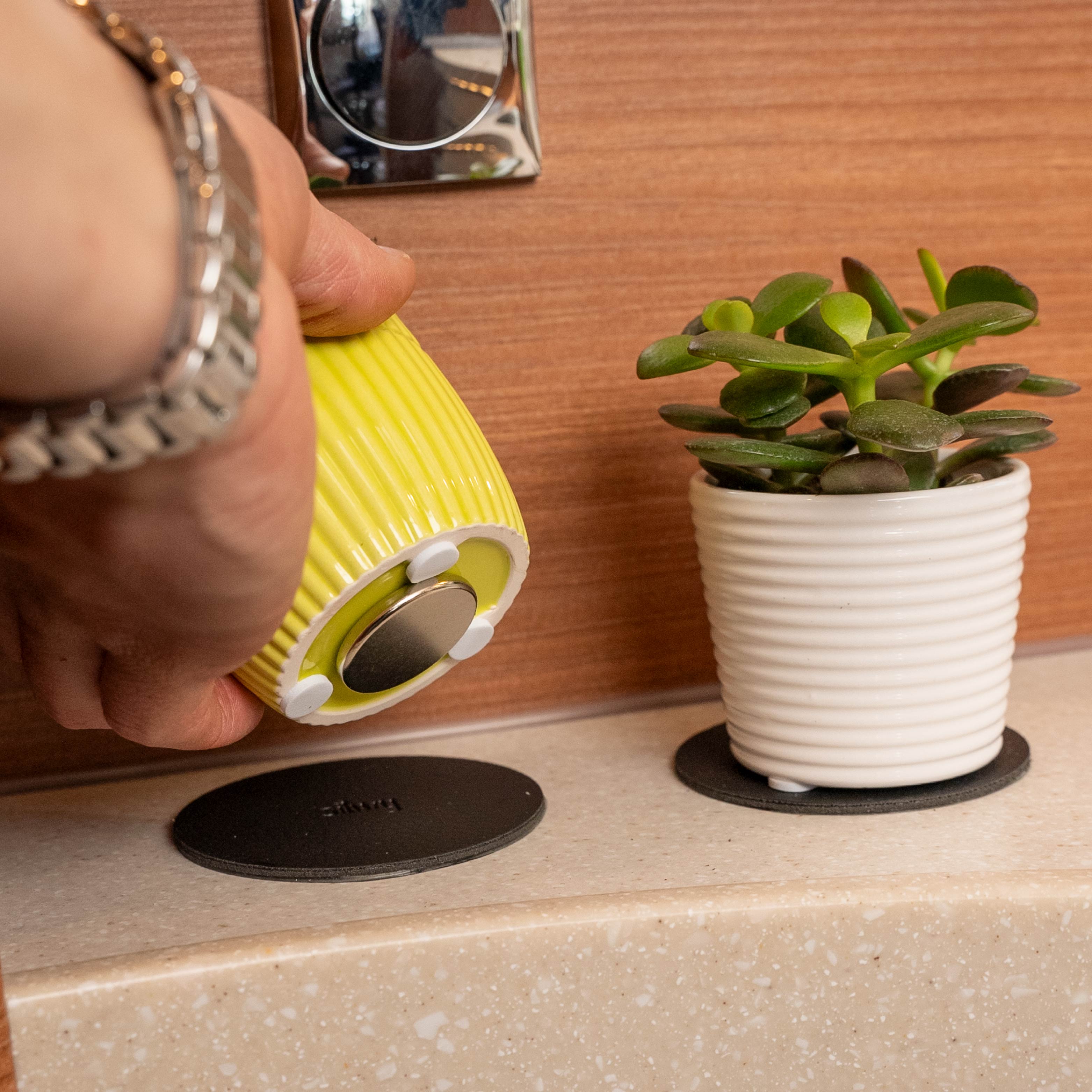 2 round metal pads in black and flower pots with magnet at the bottom in yellow and white