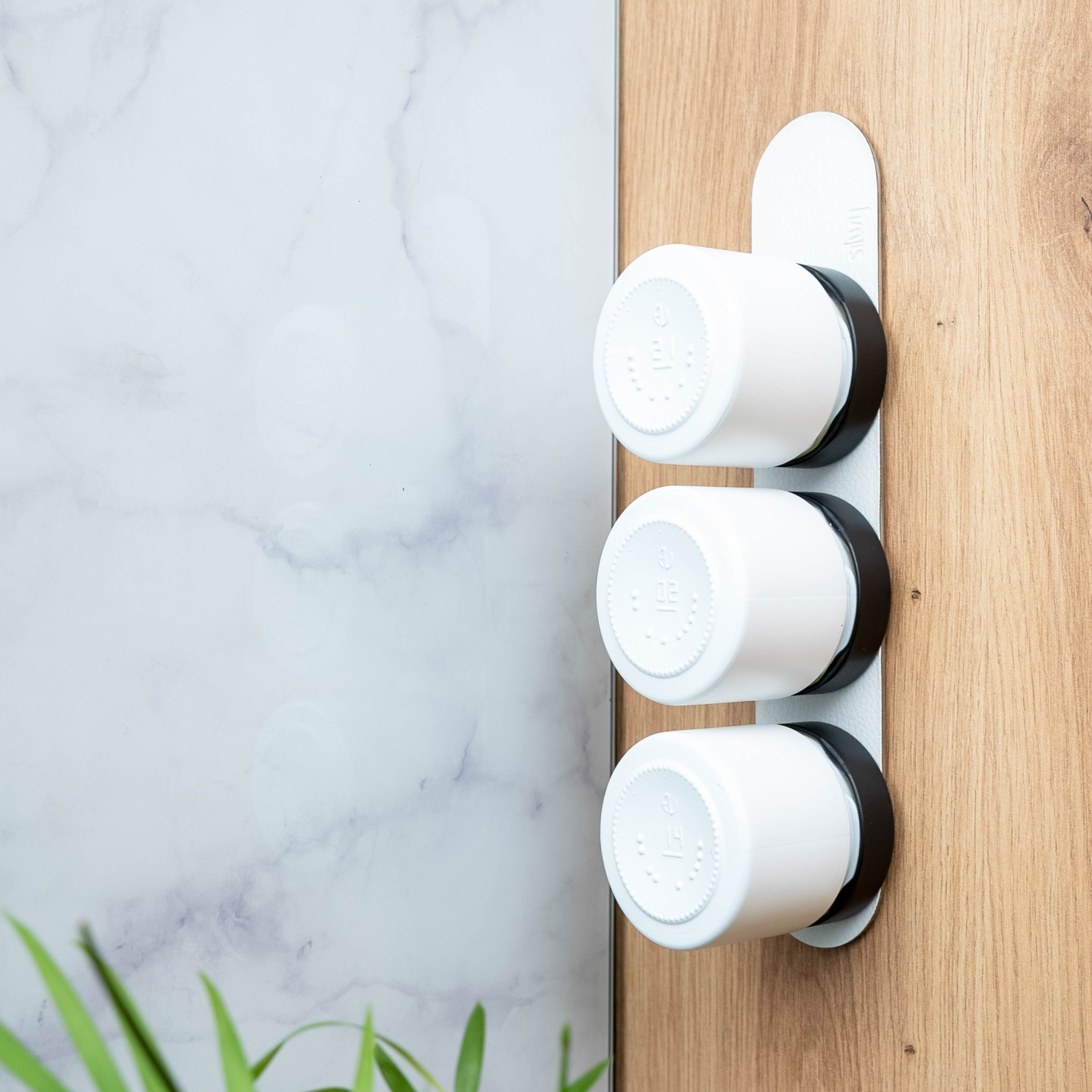 Magnetic deli jars mounted on a ledge in a kitchen environment