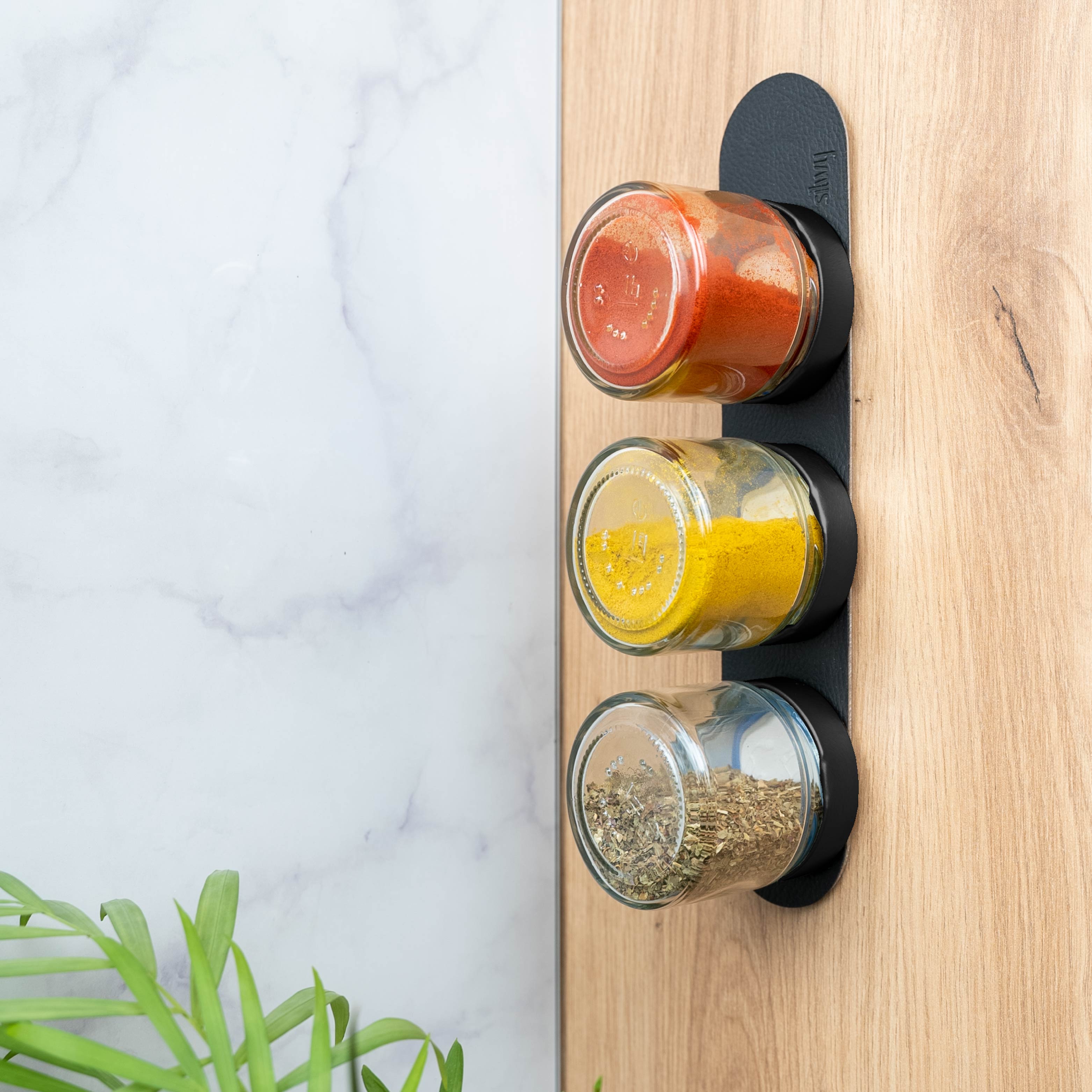 Magnetic deli jars mounted vertically on a ledge in a kitchen environment