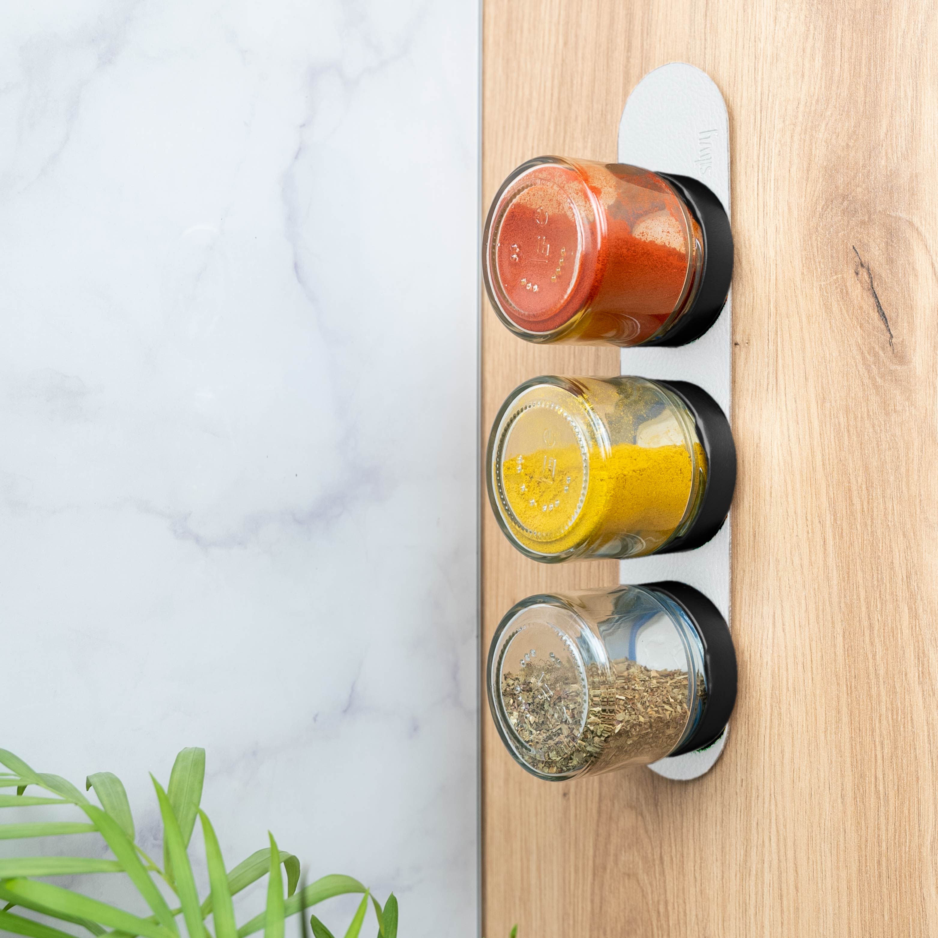 Magnetic deli jars mounted vertically on a ledge in a kitchen environment