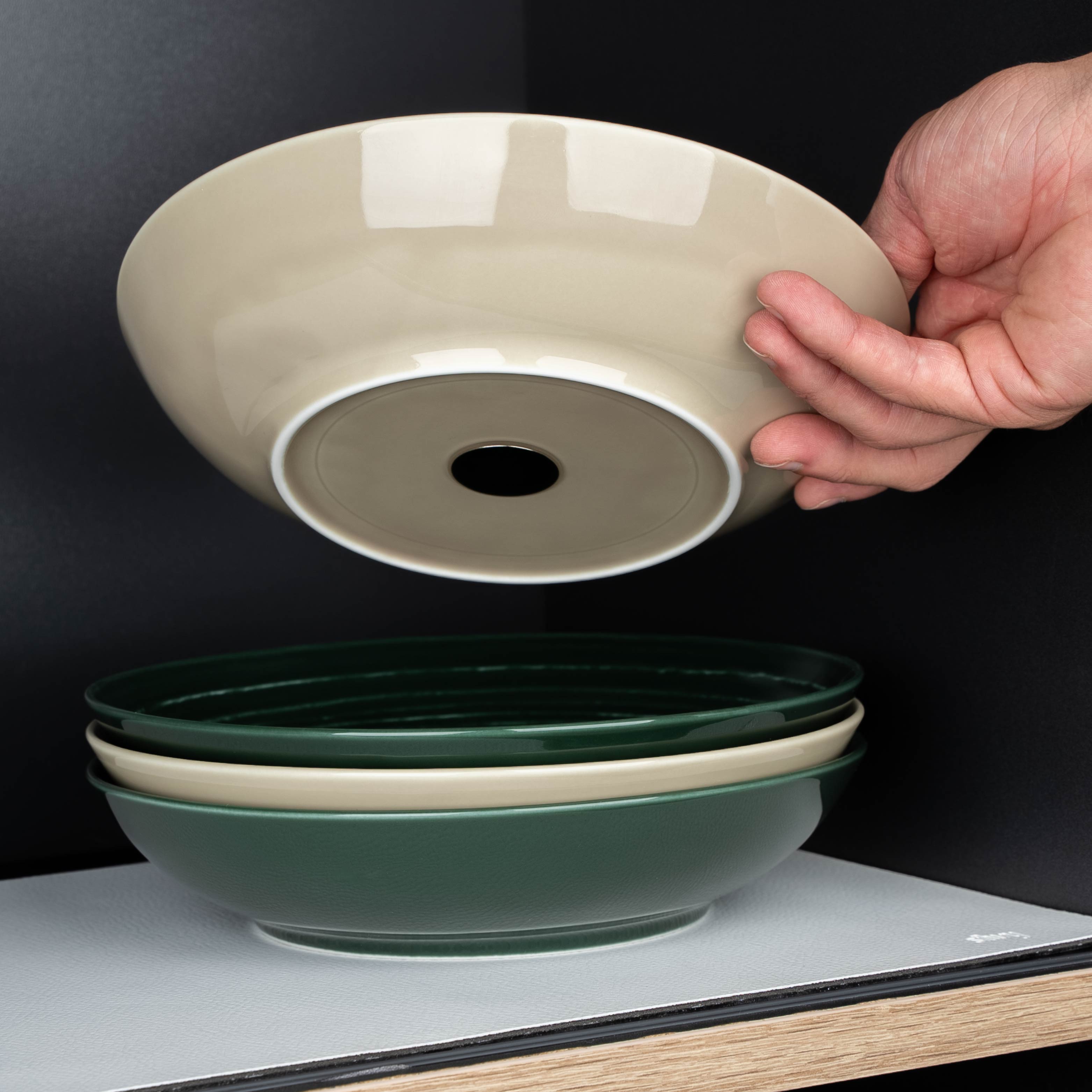 Ciotole per alimenti in porcellana nei colori Ash e Green con magneti integrati nella base su un tappetino di metallo bianco sul ripiano 