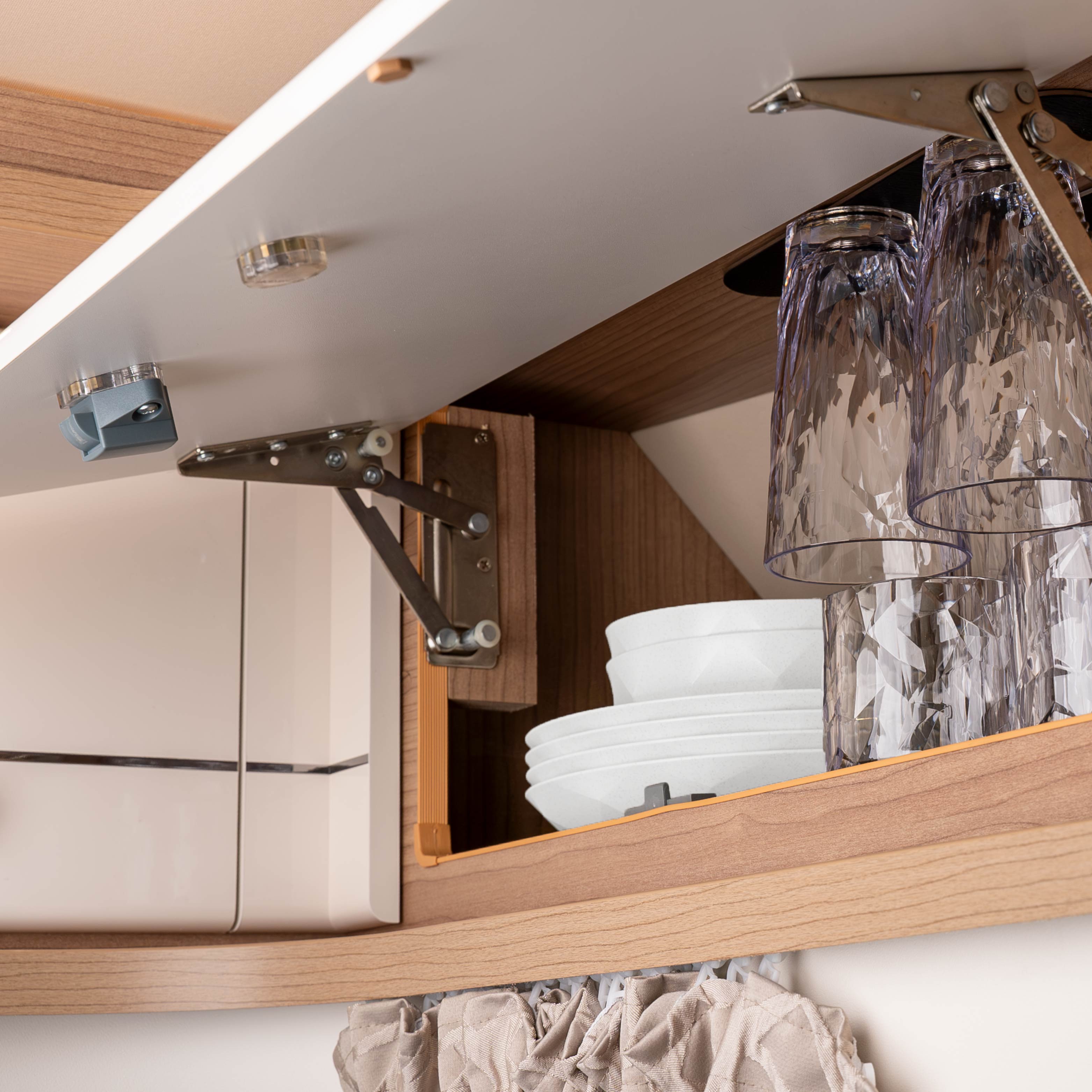 Bicchieri di plastica appesi a testa in giù alla barra metallica con magnete in un armadio di un camper
