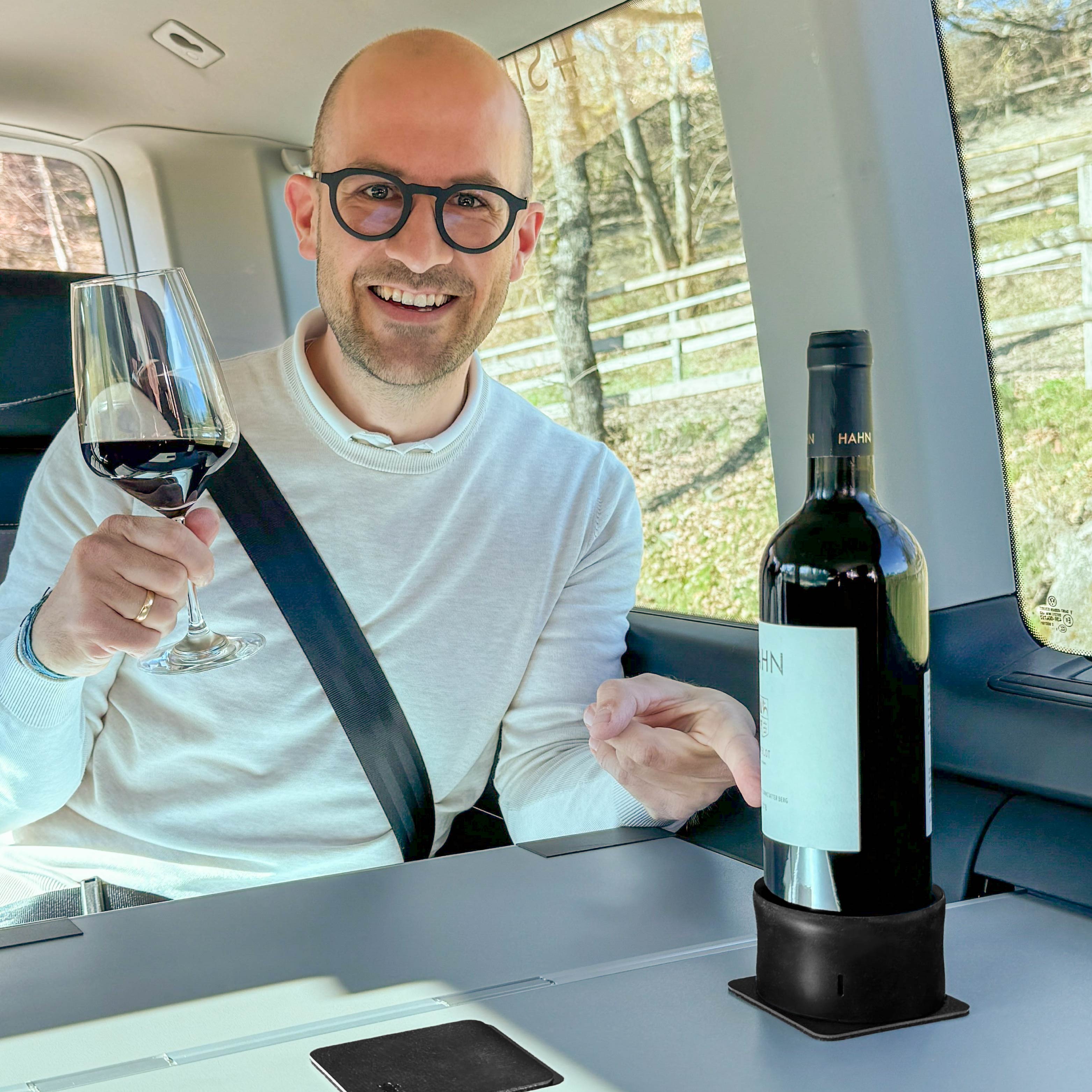 Supporto magnetico con bottiglia di vino, la persona sul sedile posteriore tiene il bicchiere in mano